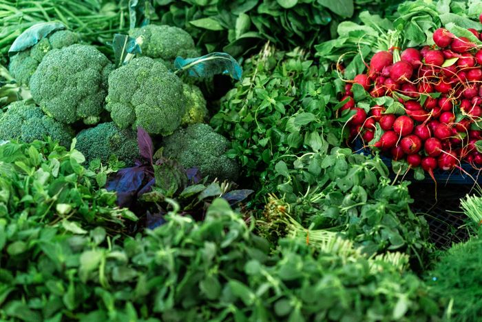 Broccoli, bladgrönsaker och rädisor på en marknad